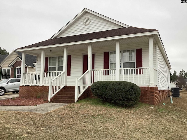 view of front facade with a front lawn, a porch, and central AC unit