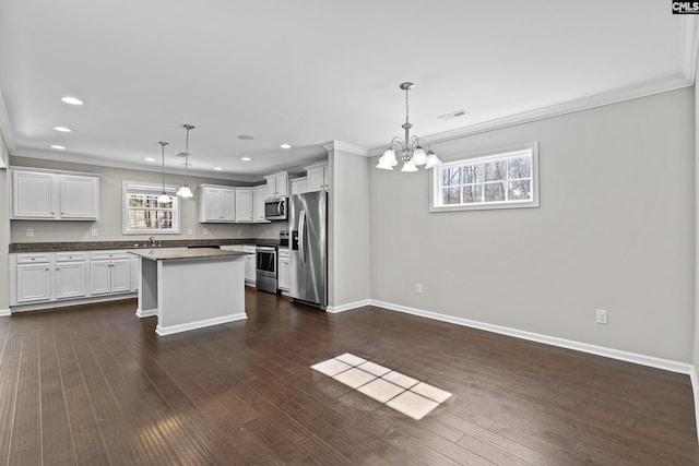 kitchen featuring hanging light fixtures, a center island, appliances with stainless steel finishes, and white cabinets