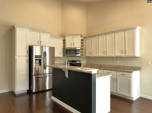 kitchen featuring a center island with sink, stainless steel appliances, light stone countertops, and white cabinets