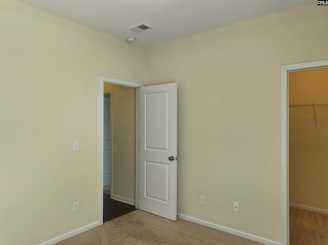 unfurnished bedroom with light carpet, a closet, and a spacious closet