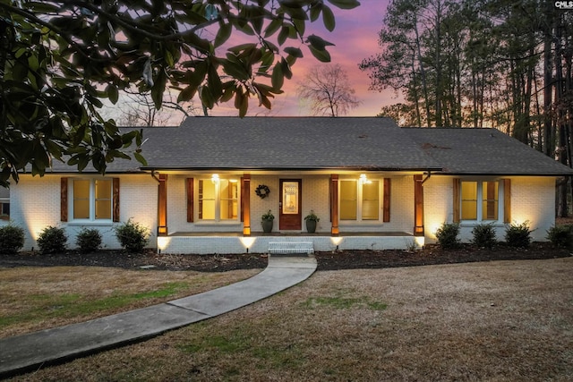 ranch-style home featuring a lawn and a porch