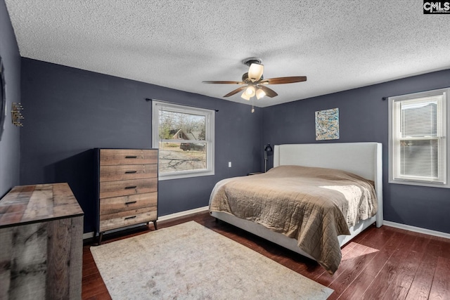 bedroom with a textured ceiling, dark hardwood / wood-style floors, and ceiling fan