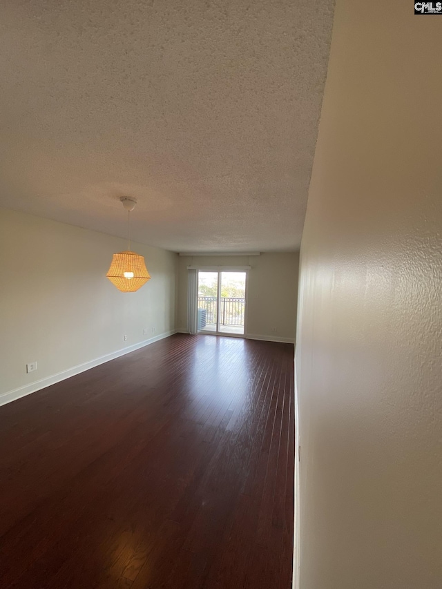 spare room with a textured ceiling and dark wood-type flooring