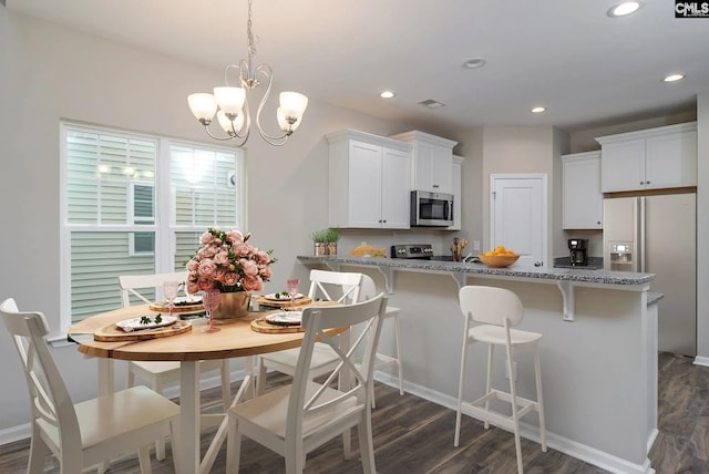 kitchen featuring white cabinetry, stainless steel appliances, light stone counters, and a breakfast bar