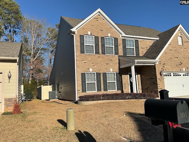 view of front facade with a front lawn, central air condition unit, and a garage