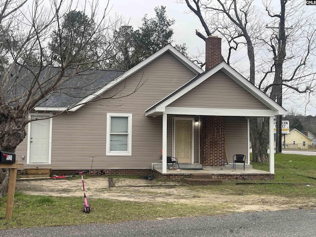 bungalow featuring a chimney and a front lawn