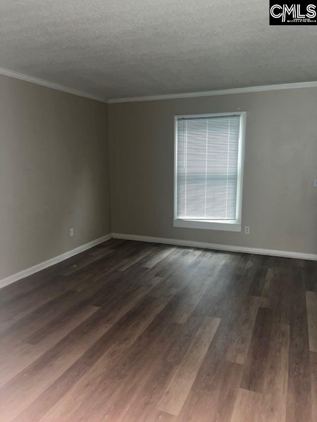 unfurnished room featuring ornamental molding, dark wood-type flooring, and a textured ceiling