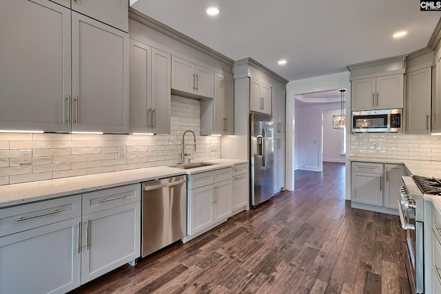 kitchen with appliances with stainless steel finishes, sink, light stone counters, dark wood-type flooring, and hanging light fixtures