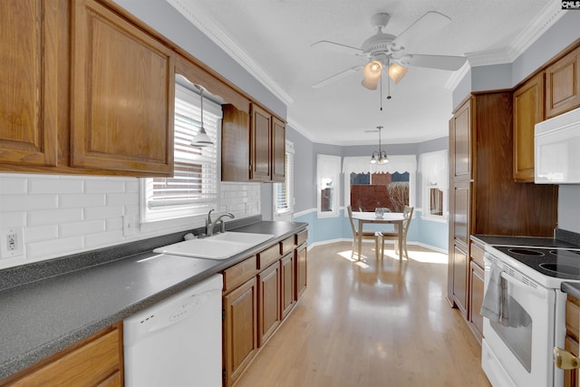 kitchen with light hardwood / wood-style floors, sink, white appliances, crown molding, and pendant lighting