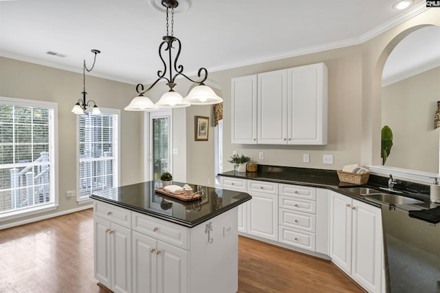 kitchen featuring sink, light hardwood / wood-style flooring, white cabinetry, and pendant lighting