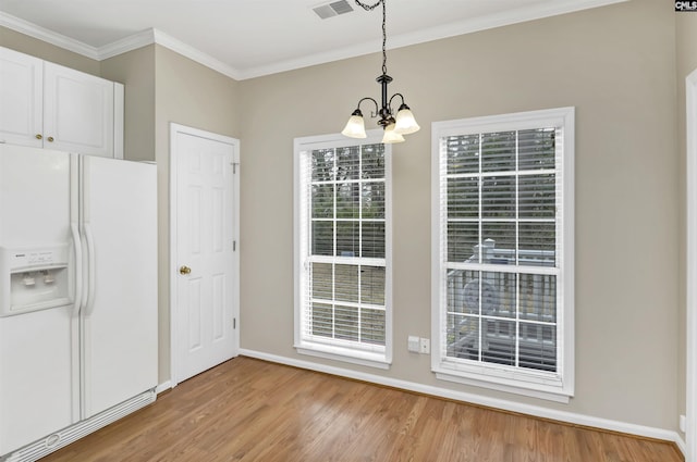 unfurnished dining area with light hardwood / wood-style floors, a chandelier, and ornamental molding