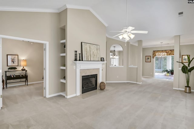 carpeted living room with crown molding, a tile fireplace, built in shelves, and ceiling fan with notable chandelier