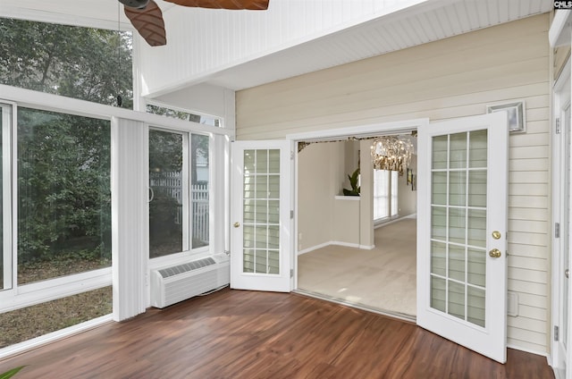 unfurnished sunroom featuring ceiling fan with notable chandelier and a wall mounted AC