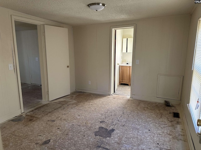 unfurnished bedroom with a textured ceiling and connected bathroom