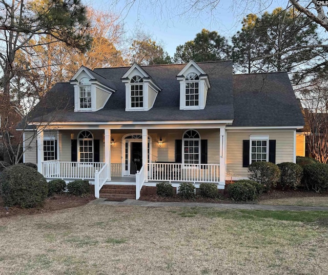 cape cod home with a front yard and a porch