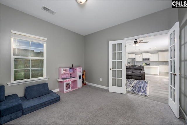 recreation room featuring ceiling fan, french doors, and light colored carpet