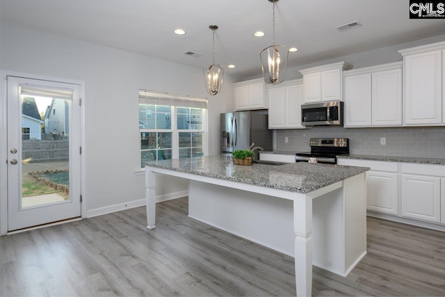 kitchen with a center island with sink, a breakfast bar, stainless steel appliances, and white cabinets