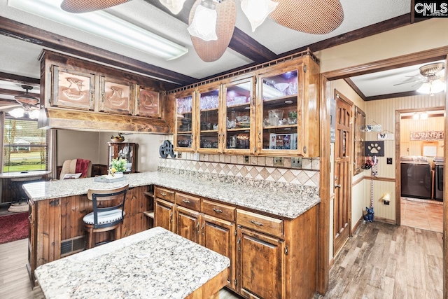 kitchen with washer and dryer, light hardwood / wood-style floors, crown molding, ceiling fan, and kitchen peninsula