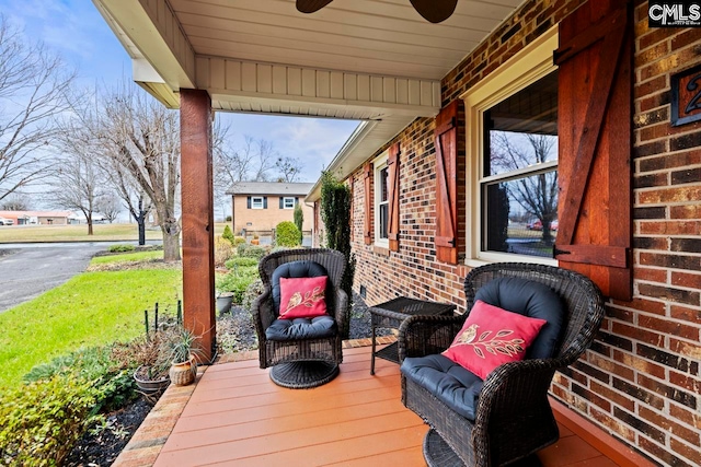 wooden terrace featuring covered porch and ceiling fan