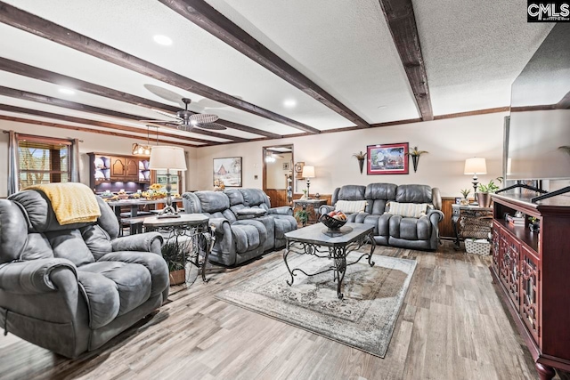 living room with a textured ceiling, beamed ceiling, ceiling fan, and light hardwood / wood-style flooring