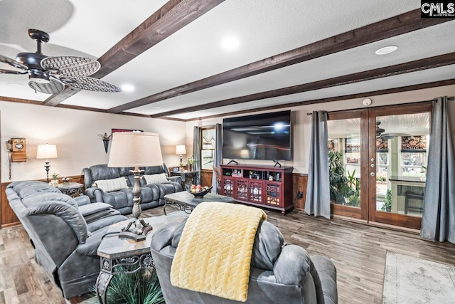 living room featuring ceiling fan, beamed ceiling, a textured ceiling, and hardwood / wood-style floors