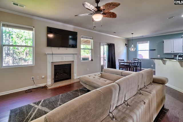 living room with visible vents, dark wood-type flooring, a fireplace, crown molding, and baseboards