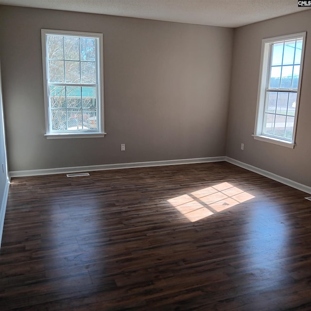 spare room featuring a textured ceiling and dark hardwood / wood-style floors