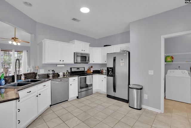 kitchen with sink, washer / dryer, white cabinets, and stainless steel appliances