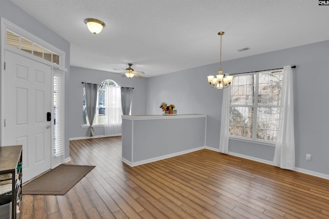 entrance foyer featuring ceiling fan with notable chandelier, wood-type flooring, and a textured ceiling