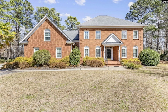 view of front of house with brick siding, roof with shingles, and a front yard