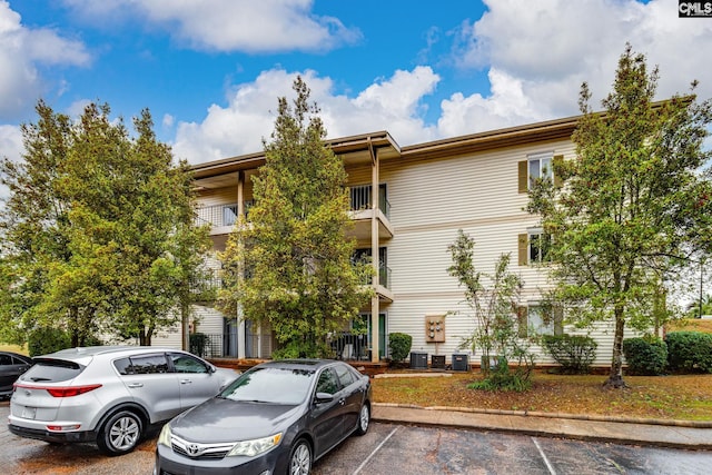 view of property with uncovered parking and central air condition unit