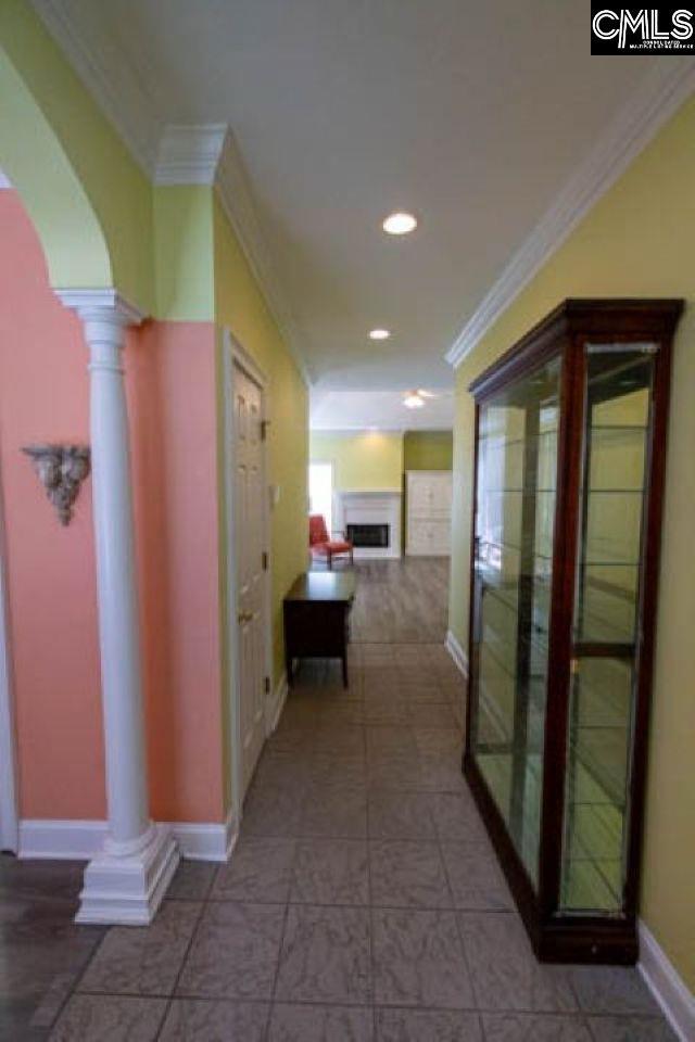 hallway featuring ornate columns, arched walkways, and ornamental molding