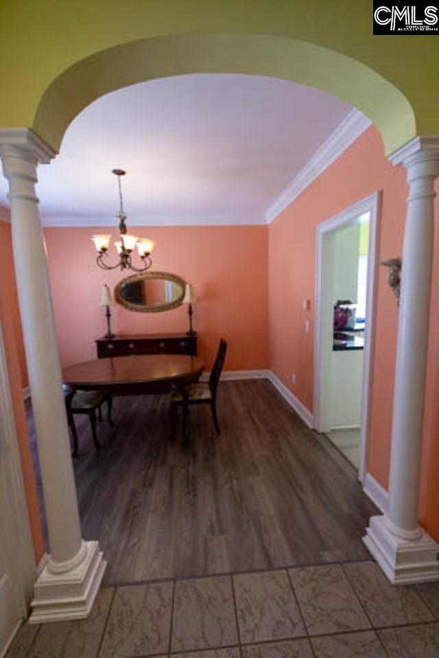 dining space with crown molding, arched walkways, and ornate columns