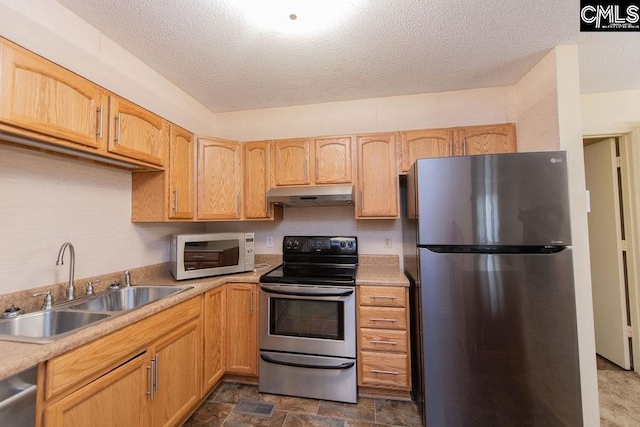 kitchen featuring stainless steel appliances, light countertops, a sink, a textured ceiling, and under cabinet range hood