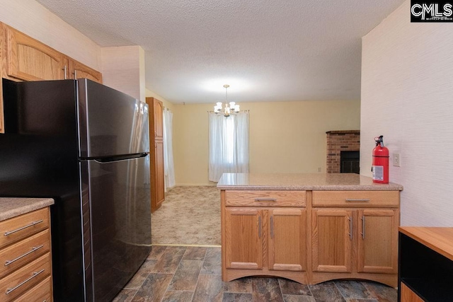 kitchen featuring light countertops, hanging light fixtures, freestanding refrigerator, a textured ceiling, and a peninsula