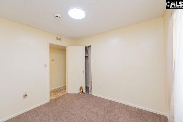 unfurnished room with carpet flooring, visible vents, and baseboards