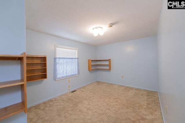 carpeted empty room featuring visible vents, a textured ceiling, and baseboards