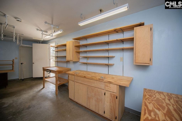 kitchen featuring concrete flooring, light brown cabinetry, butcher block countertops, and open shelves