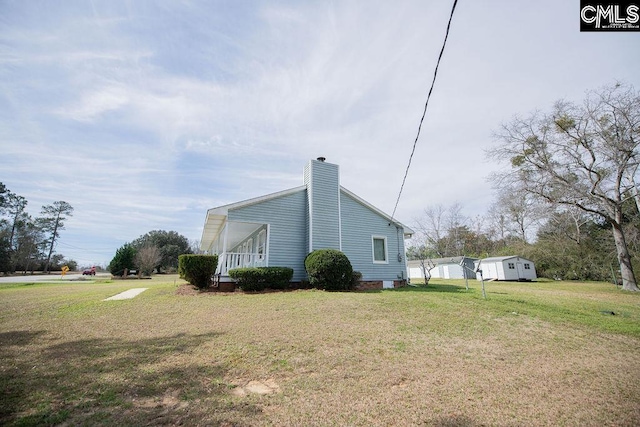 view of side of property featuring a chimney and a lawn