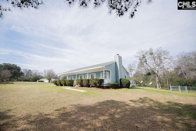 view of side of property featuring a yard, a chimney, and fence