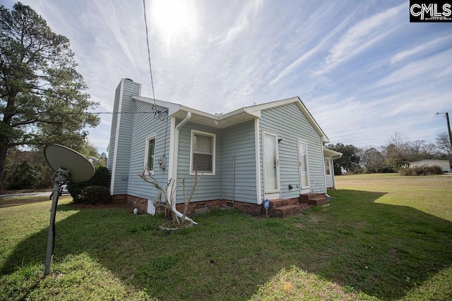 view of side of property with crawl space, a chimney, and a yard