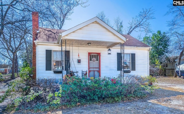 bungalow-style home with a shingled roof, fence, and a chimney