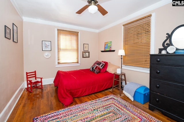 bedroom featuring baseboards, dark wood-style flooring, a ceiling fan, and crown molding