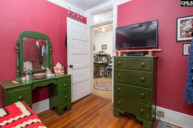 bedroom with dark wood-style floors and wallpapered walls