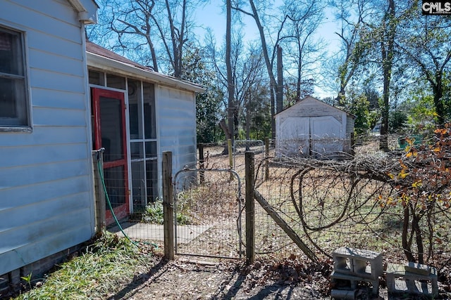 view of yard with a shed, a gate, fence, and an outdoor structure