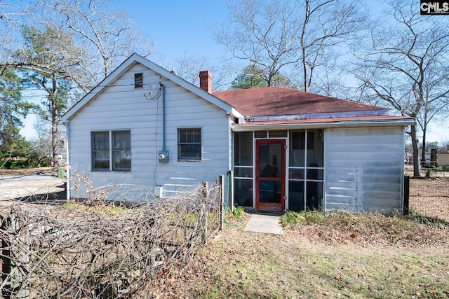 rear view of house with a chimney and a sunroom