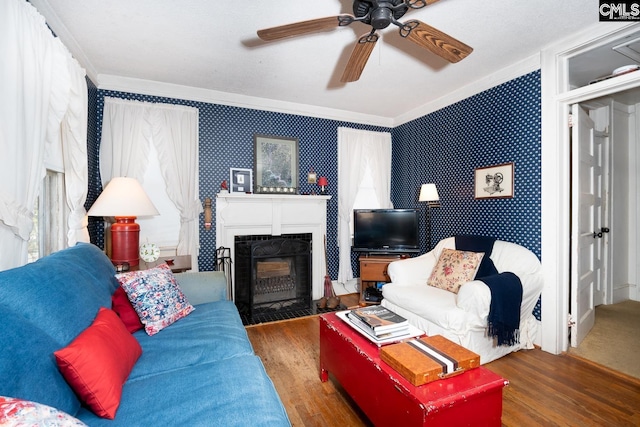 living room featuring a fireplace with flush hearth, dark wood finished floors, a ceiling fan, and wallpapered walls