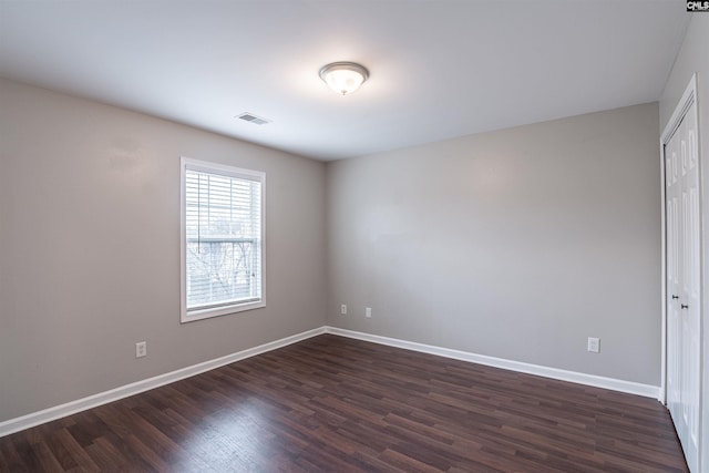 unfurnished room featuring dark wood-style floors, baseboards, and visible vents