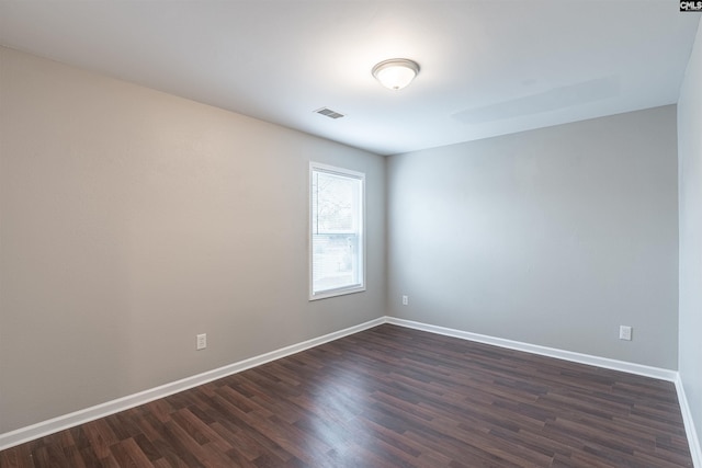 empty room with visible vents, baseboards, and dark wood finished floors