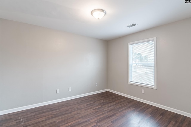 spare room featuring baseboards, visible vents, and dark wood-type flooring